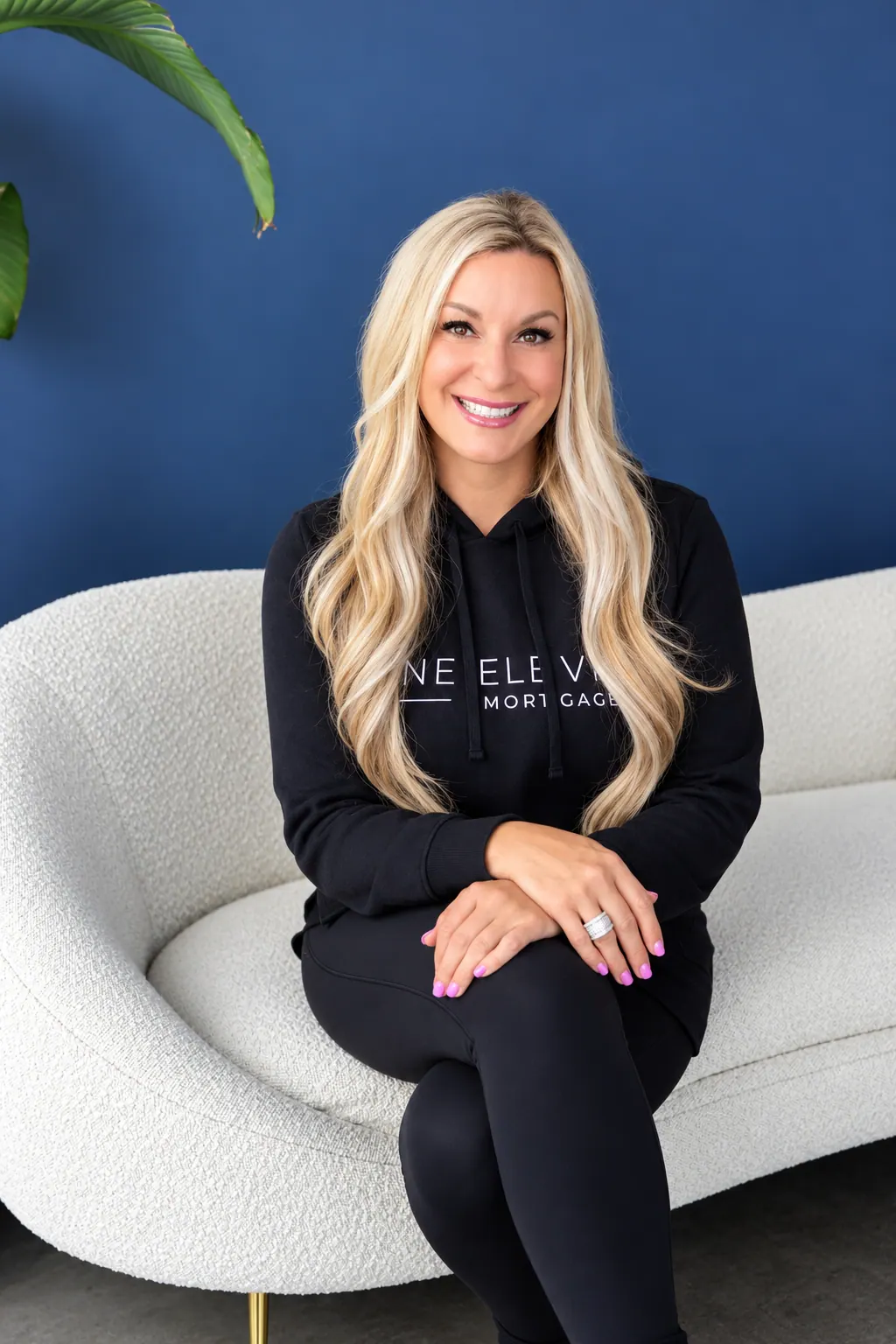 Kahren Oxner in a One Eleven Mortgage hoodie on a sofa